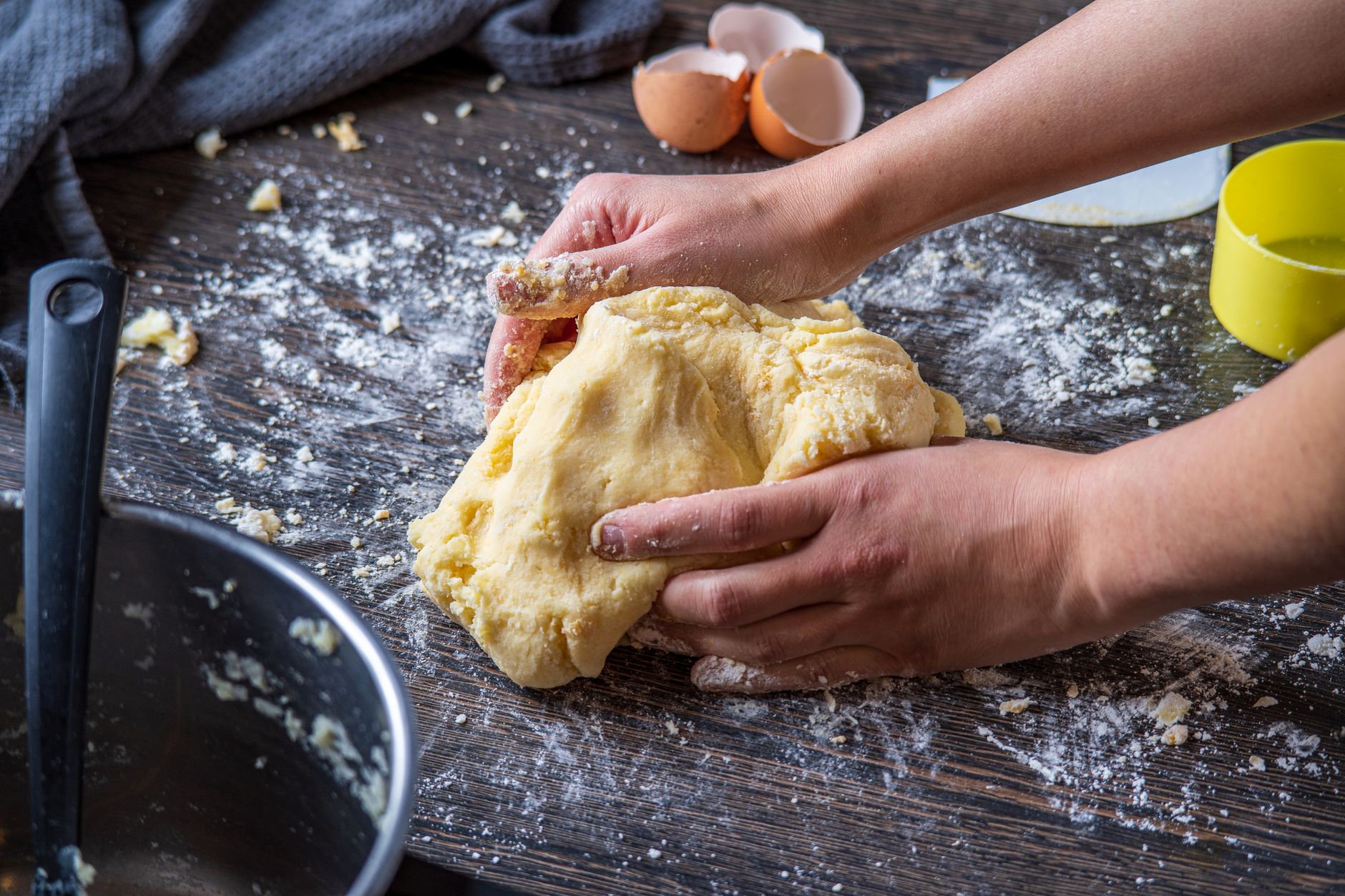 Close-up of hands kneading dough on a floured wooden surface.
