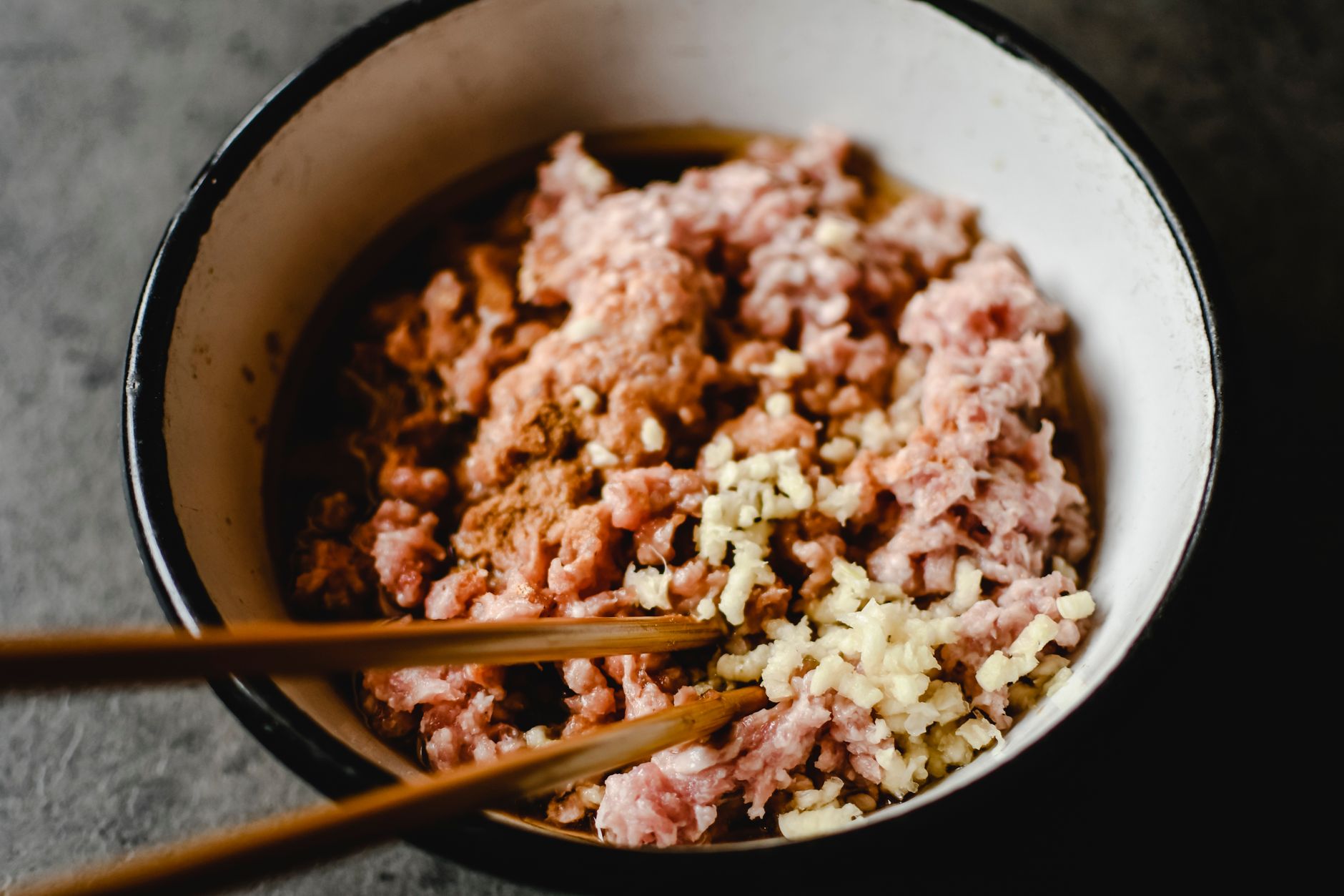 Close-up of minced filling and chopped garlic in a bowl.